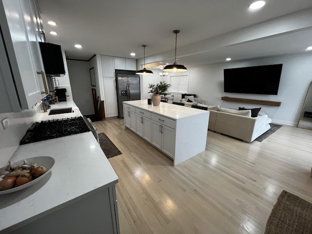 kitchen with white cabinets, light stone countertops, stainless steel fridge with ice dispenser, and hanging light fixtures