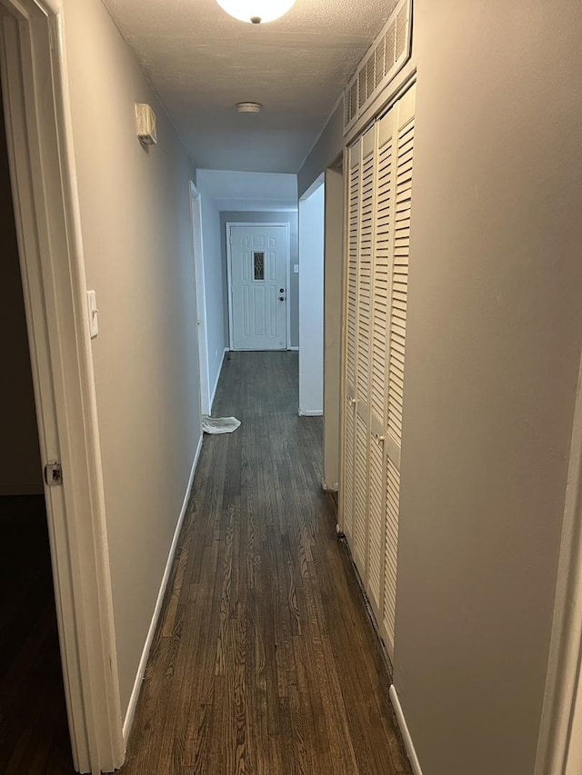 hall with a textured ceiling and dark hardwood / wood-style floors