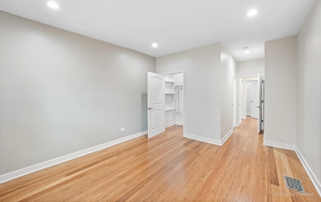 unfurnished bedroom featuring a walk in closet and light wood-type flooring