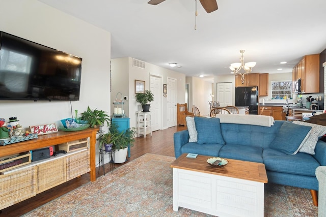 living room with ceiling fan with notable chandelier and dark wood-type flooring