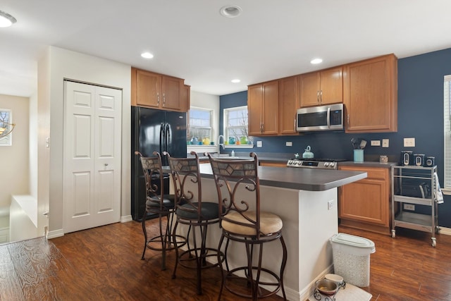 kitchen with stove, sink, dark hardwood / wood-style floors, a kitchen island, and a kitchen bar