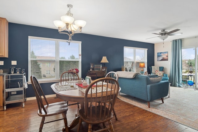 dining space with ceiling fan with notable chandelier, dark wood-type flooring, and a wealth of natural light