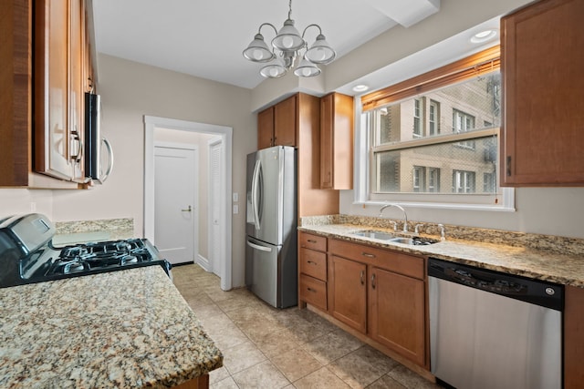 kitchen featuring light stone counters, sink, stainless steel appliances, and a chandelier