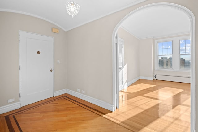 foyer entrance featuring a chandelier, ornamental molding, light hardwood / wood-style flooring, and a baseboard heating unit