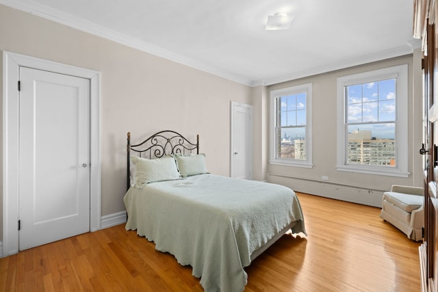 bedroom featuring light wood-type flooring, ornamental molding, and a baseboard radiator