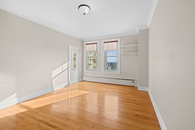 unfurnished room with ornamental molding, light wood-type flooring, and a baseboard heating unit