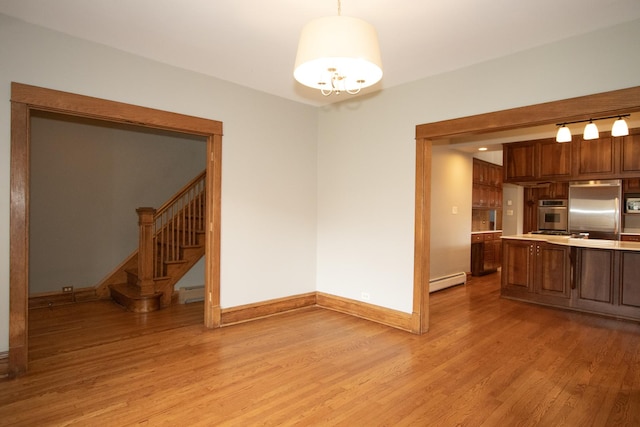 kitchen featuring hanging light fixtures, baseboard heating, light wood-type flooring, and stainless steel appliances