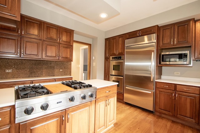 kitchen featuring light wood-type flooring, built in appliances, and tasteful backsplash