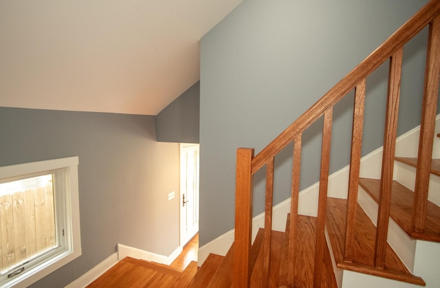 staircase featuring wood-type flooring and vaulted ceiling