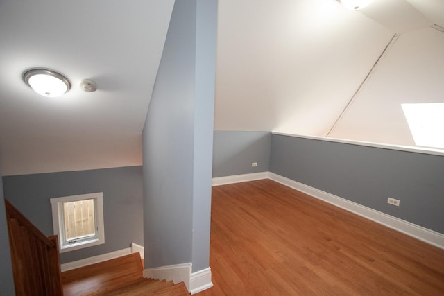 stairway with lofted ceiling and hardwood / wood-style floors