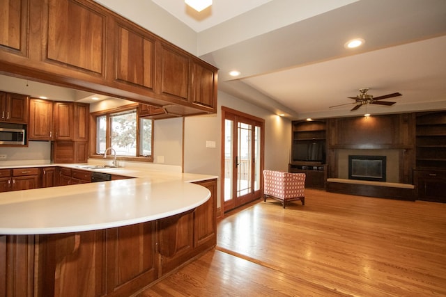 kitchen with ceiling fan, kitchen peninsula, sink, and light hardwood / wood-style flooring