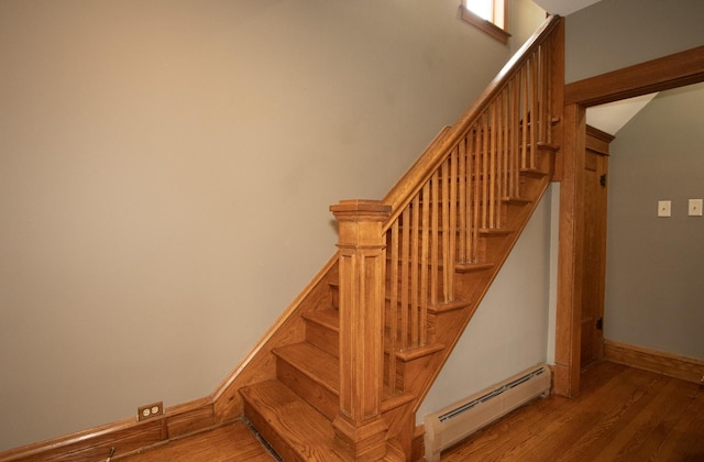 staircase with wood-type flooring and a baseboard radiator