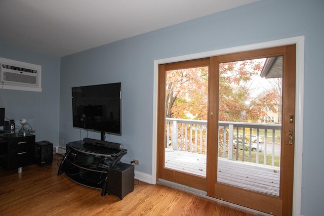 living room with light hardwood / wood-style floors, plenty of natural light, and an AC wall unit