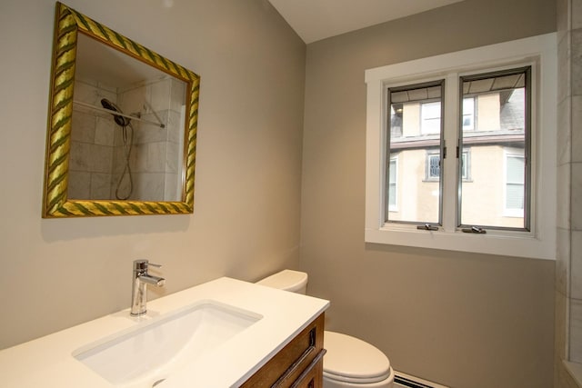 bathroom with toilet, vanity, a baseboard heating unit, and a shower