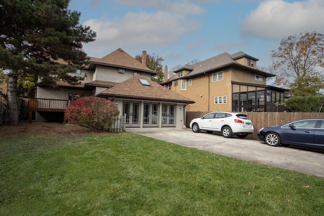 rear view of property featuring french doors and a lawn