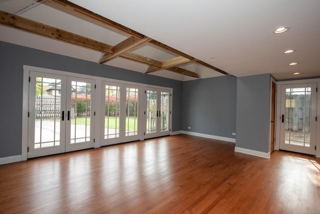 unfurnished living room with light wood-type flooring, coffered ceiling, french doors, and beamed ceiling