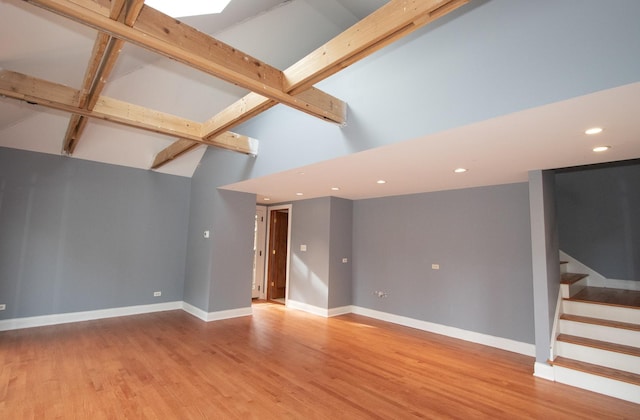 unfurnished living room featuring light hardwood / wood-style floors, beam ceiling, and high vaulted ceiling