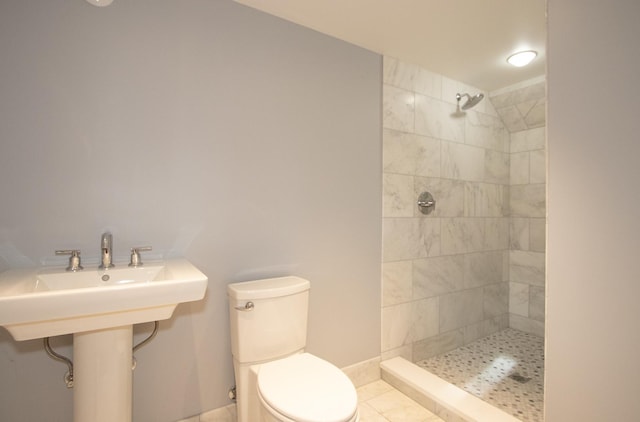 bathroom featuring toilet, tile patterned flooring, and a tile shower