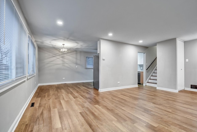 empty room featuring a chandelier and light hardwood / wood-style flooring