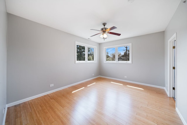 empty room with baseboards, a ceiling fan, and light wood-style flooring