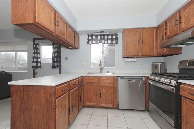 kitchen featuring stainless steel appliances, kitchen peninsula, sink, and light tile patterned floors