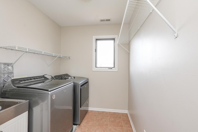 clothes washing area with washer and clothes dryer, light tile patterned flooring, and sink