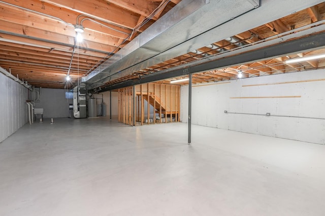 basement featuring sink, heating unit, and water heater