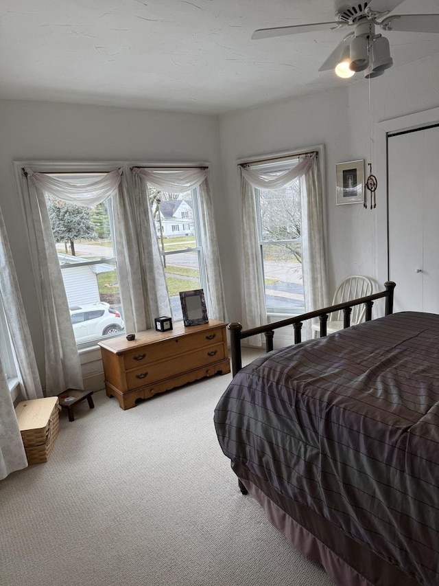 carpeted bedroom featuring multiple windows and ceiling fan