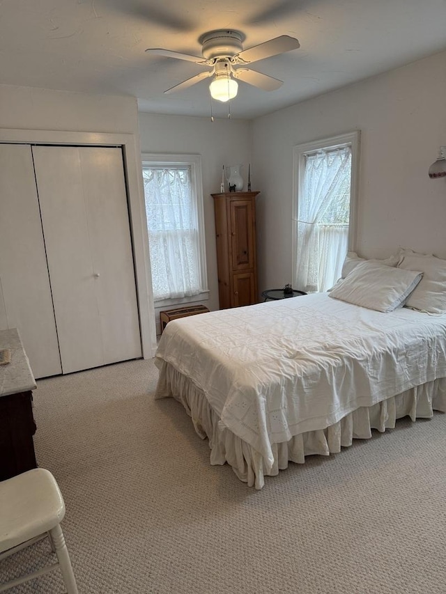 bedroom with multiple windows, ceiling fan, a closet, and carpet floors