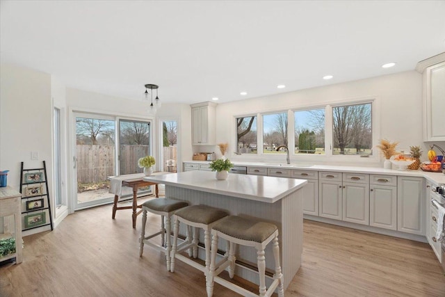 kitchen with plenty of natural light, a kitchen island, hanging light fixtures, and light wood-type flooring