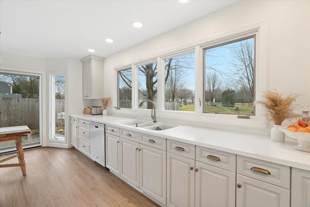 kitchen with white cabinetry, dishwasher, light wood-type flooring, and sink