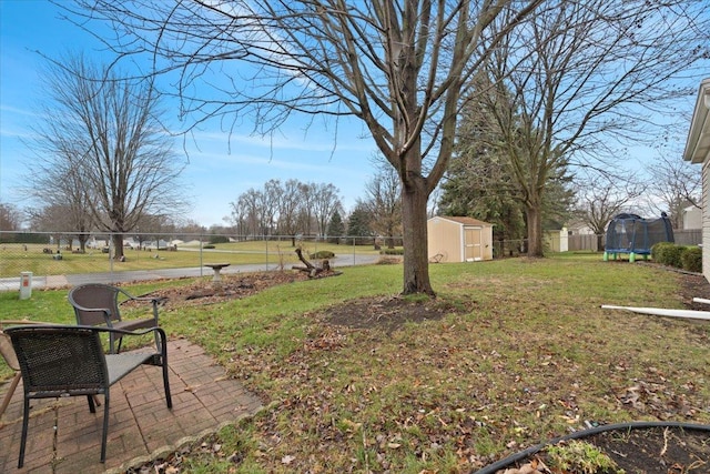 view of yard with a trampoline, a patio area, and a storage shed