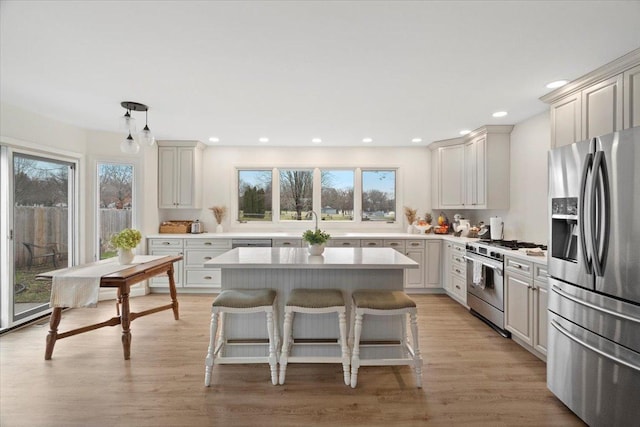 kitchen with a center island, stainless steel appliances, pendant lighting, light hardwood / wood-style floors, and a breakfast bar area