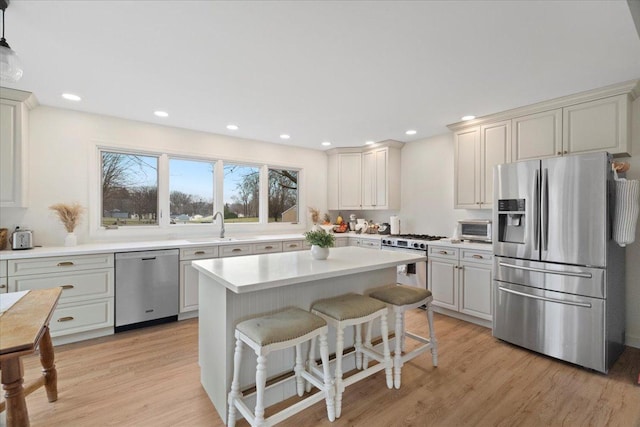 kitchen featuring appliances with stainless steel finishes, light wood-type flooring, a kitchen island, and sink