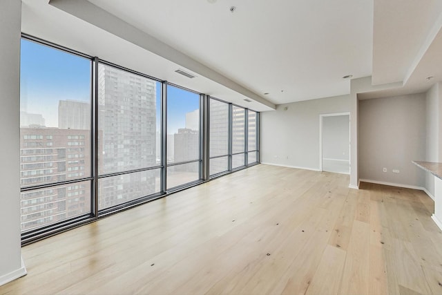 spare room with floor to ceiling windows, light hardwood / wood-style floors, and plenty of natural light