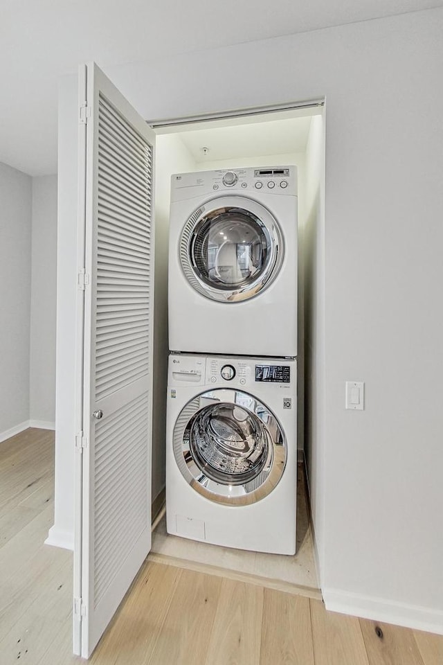 laundry room featuring stacked washer and dryer and hardwood / wood-style floors