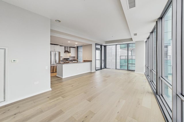 unfurnished living room with floor to ceiling windows and light wood-type flooring