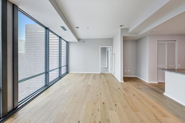 unfurnished living room with floor to ceiling windows and light wood-type flooring