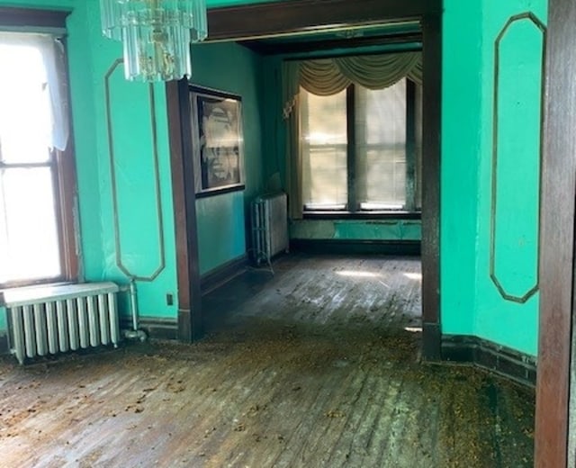 misc room with dark hardwood / wood-style floors, radiator heating unit, and an inviting chandelier