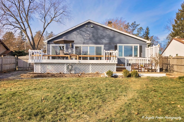 back of property with a lawn and a wooden deck