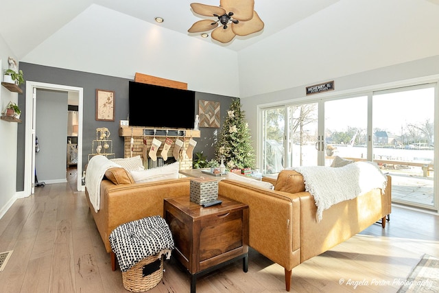 living room featuring ceiling fan, vaulted ceiling, and light wood-type flooring