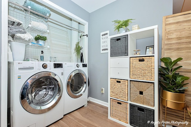 clothes washing area with washer and dryer and light hardwood / wood-style floors