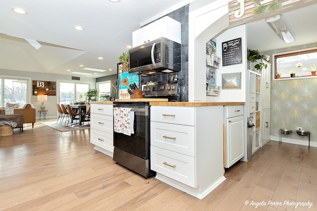 kitchen featuring wooden counters, appliances with stainless steel finishes, white cabinets, and light hardwood / wood-style flooring