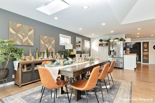 dining area featuring light hardwood / wood-style flooring and a skylight