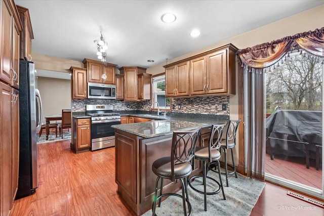 kitchen with tasteful backsplash, a kitchen bar, light hardwood / wood-style floors, and appliances with stainless steel finishes