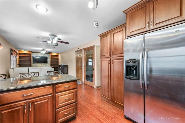 kitchen featuring ceiling fan, stainless steel fridge, dark stone countertops, and light hardwood / wood-style floors