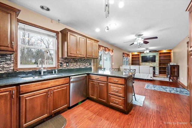 kitchen featuring dishwasher, decorative backsplash, light wood-type flooring, and sink