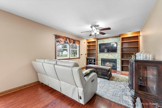 living room featuring dark hardwood / wood-style flooring, a stone fireplace, and ceiling fan