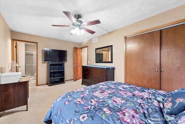 bedroom featuring ceiling fan, light colored carpet, ensuite bathroom, and a closet