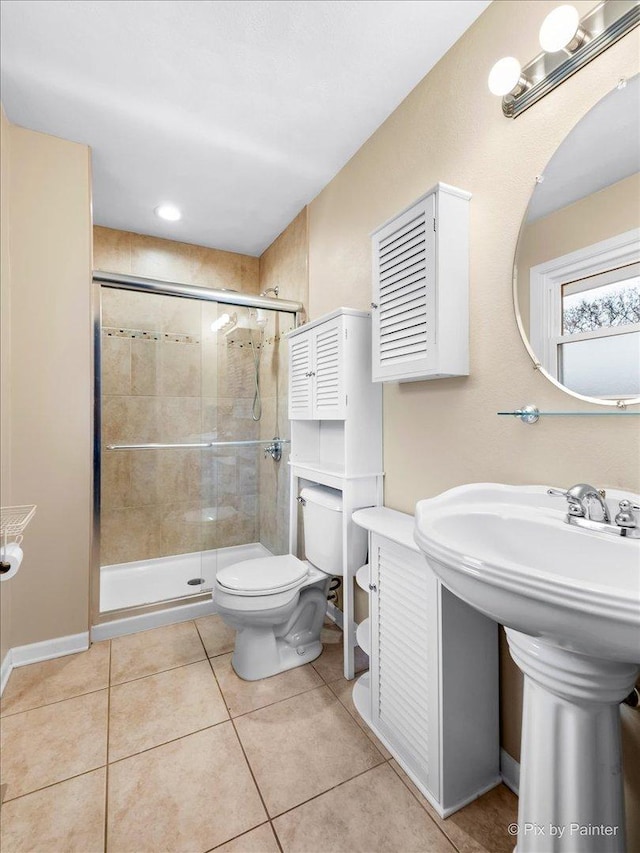 bathroom with walk in shower, sink, tile patterned flooring, and toilet